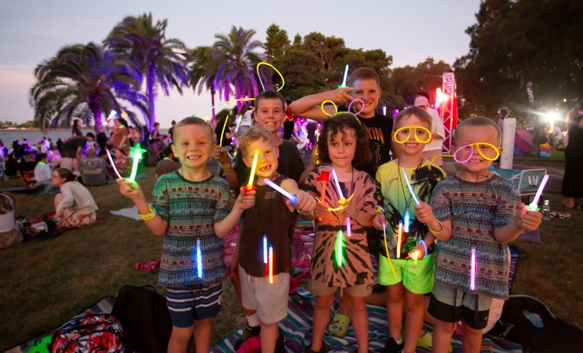 Kids waving and wearing colourful glowsticks to celebrate NYE