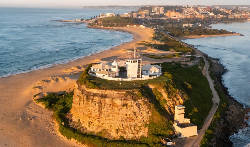 Aerial view of Nobbys Lighthouse overlooking Newcastle’s coastline, at sunrise.