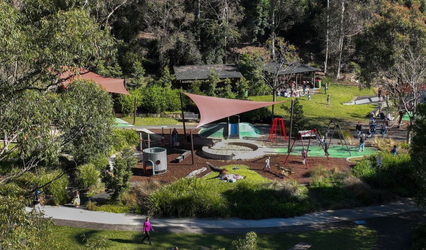 Blackbutt Playground offers a nature-inspired setting with accessible features, interactive displays, a group swing, and a sensory garden.