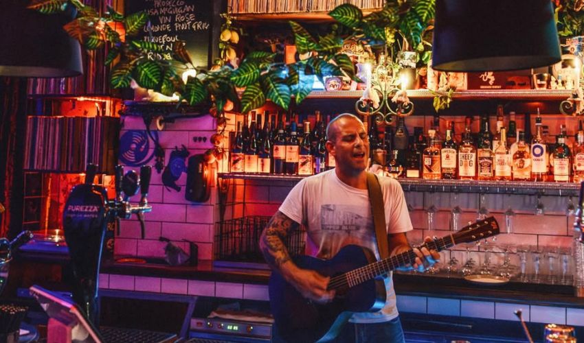 A musician plays the guitar behind the bar at Mad Poet. 