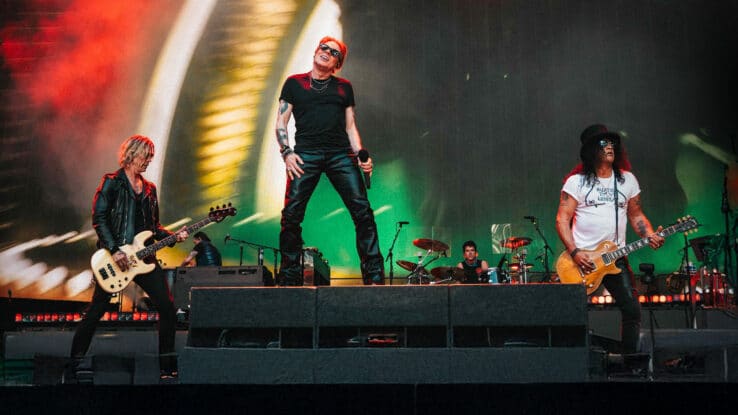 Guns N' Roses performing live on stage in front of a large crowd during a concert.