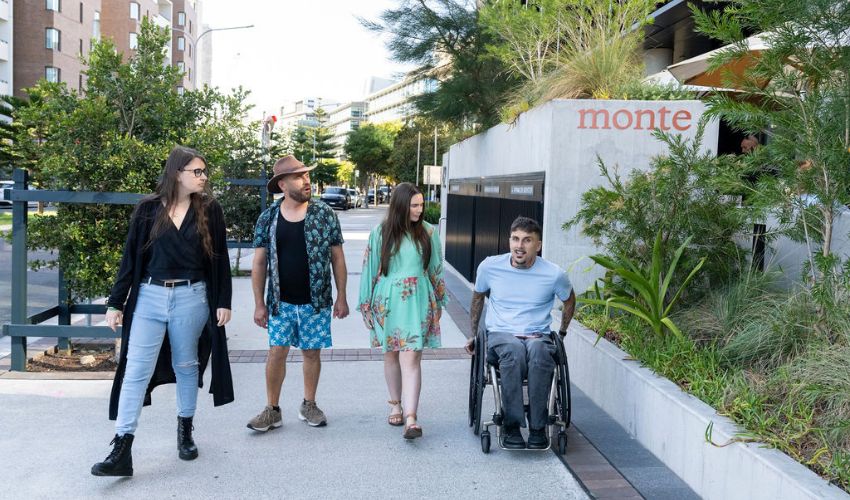 Four friends, including a wheelchair user, outside Monte Café in Honeysuckle, Newcastle, beneath the Little National Hotel.