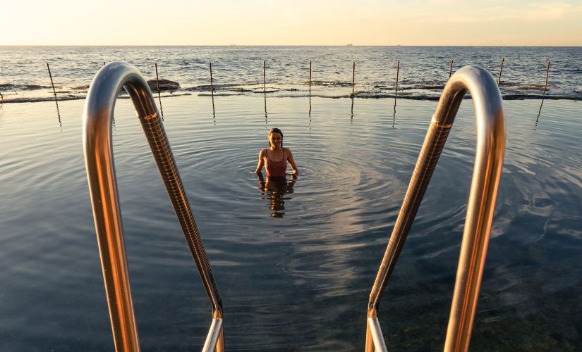 People swimming and relaxing in the Bogey Hole ocean pool on Newcastle's rocky coastline.