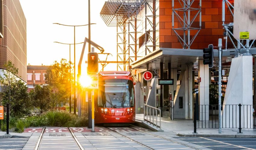 Light rail stops at the Newcastle Interchange with the sun peaking through in the background.